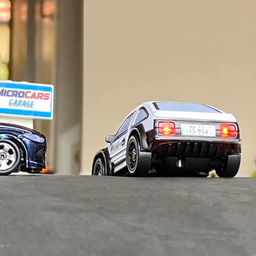 Model cars on a display stand with a 'Microcars Garage' sign in the background.